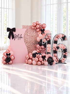Décor Sweet 16 Boucles et Paillettes, mur à paillettes rose gold, panneau prénom avec boucles en velours noir, guirlande de ballons rose et noir et chiffre 16 géant garni de ballons