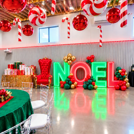 Party de bureau de Noël monté dans la salle, lettres lumineuses NOEL, sapin et trône
